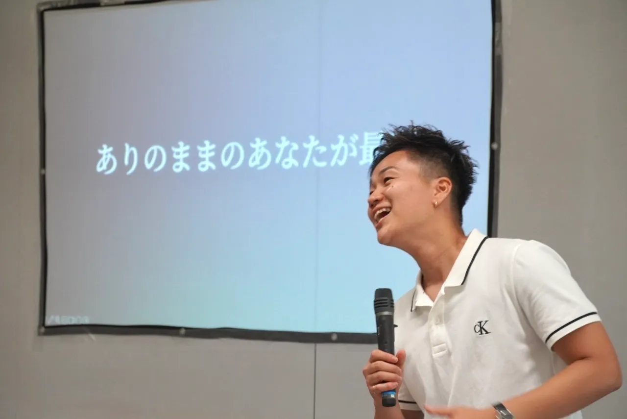講演する谷川彩莉。スクリーンには「ありのままのあなたが最高」の文字